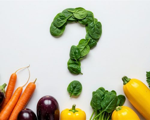 question-mark-made-spinach-leaves-surrounded-by-fresh-vegetables-including-carrots-zucchini-eggplants-bell-peppers-white-surface-healthy-eating-concept